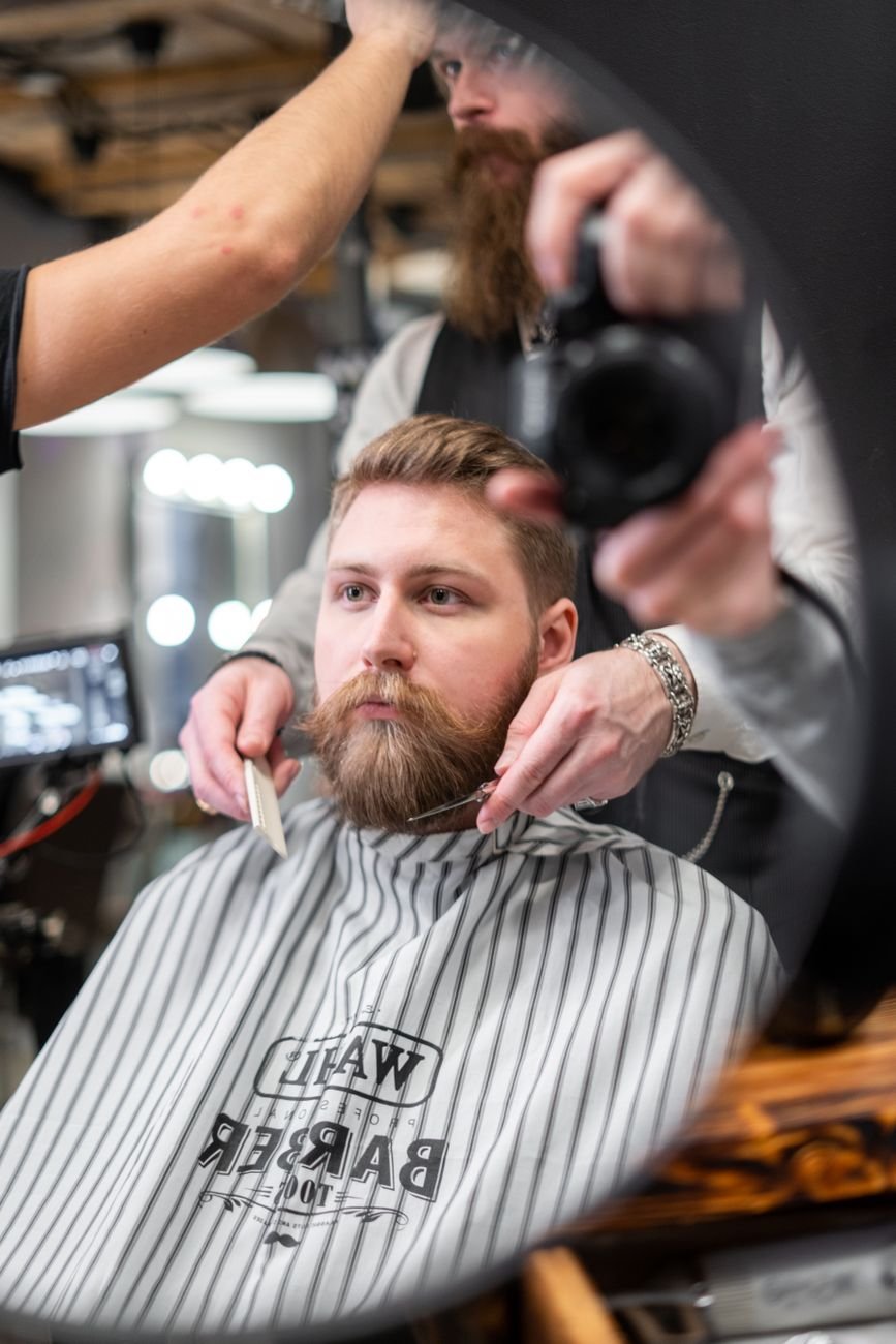 Man receiving a beard trim at a contemporary barbershop, focusing on grooming and style.